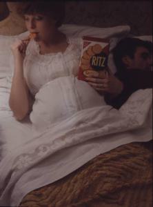 Campagna pubblicitaria Ritz Saiwa - una coppia di coniugi nel loro letto - la donna assaggia un salatino di nascosto dal marito, che dorme