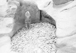 Val Verzasca - fotomodella in abito trasparente posa in piedi all'interno di un massiccio roccioso