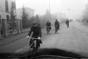 Dintorni di Reggio Emilia. Un paese dislocato ai lati della strada statale n. 173. Persone in bicicletta