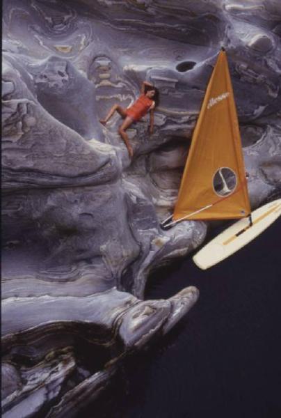 Valle Verzasca. Modella sdraiata sulla roccia. Sullo sfondo un windsurf