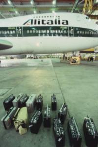 Alitalia. Interno di un hangar - aeroplano della compagnia di bandiera e valigie appoggiate sul pavimento