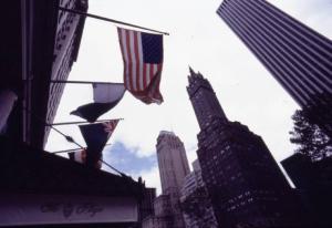 New York. Manhattan - fuga prospettica verso l'alto di grattacieli. Sventola la bandiera americana