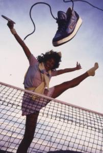 Campagna pubblicitaria Ellesse. Fotomodella indossa completo da tennis -  rete di un campo da tennis - scarpa da tennis