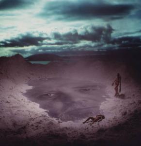 Klaustrofobia. Ritratto maschile - autoritratto dell'artista proiettato su una spiaggia. In primo piano due burattini - nudi femminili. Luce del mattino