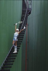 Modella con racchetta da tennis sulla scalinata di un gasometro