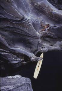 Valle Verzarsca. Modella seduta sulla roccia. Sullo sfondo un windsurf