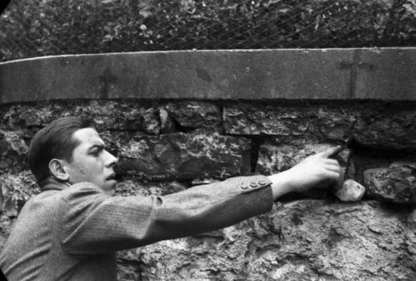 Bonzanigo - Bill e Pedro - ricostruzione dell'uccisione di Benito Mussolini - Un uomo indica un punto preciso del muro dove avvenne la fucilazione