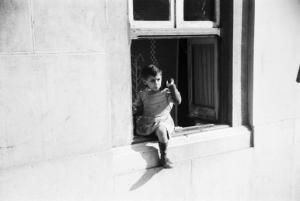 Lisbona. Bambina a cavalcioni di una finestra