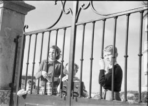 Estoril. Famiglia Savoia in esilio. Maria Pia, Maria Beatrice, Maria Gabriella e Vittorio Emanuele IV in giardino - guardano attraverso le sbarre del cancello