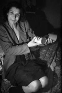 Una prostituta seduta sul letto con due barattoli in mano