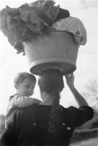 Cangas - madre trasporta sulla testa un recipiente colmo di ortaggi. Con un braccio regge il figlio