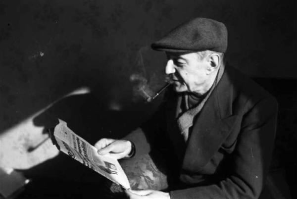 Il poeta Umberto Saba. Ritratto del poeta mentre fuma la pipa e legge il giornale