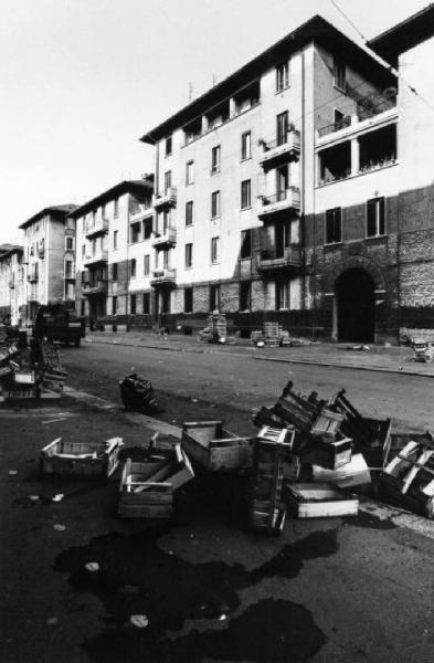 Milano. Mucchi di cassette a bordo strada di fronte alle facciate di un quartiere popolare dei primi del secolo