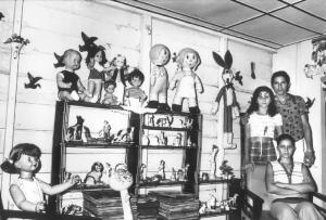 Brasile. Famiglia posa nel soggiorno della propria casa - alla parete è appoggiato uno scaffale con bambole, dischi, soprammobili