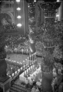Roma - Basilica di S. Pietro. Ripresa dall'alto dell'altare con sacerdoti che officiano. Si notano le colonne tortili del baldacchino in primo piano e la chiesa gremita sullo sfondo