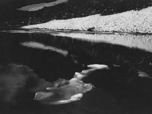Lago alpino - Tracce di ghiaccio sulla superficie - sullo sfondo pendii innevati