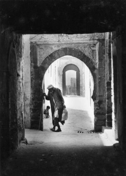 Marocco. Portico con archi ogivali, con un anziano che cammina
