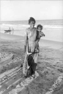 Madras. Giovane madre con in braccio il figlio e pesce nell'altra mano