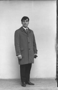 Ritratto maschile - giovane con il cappotto e i guanti in mano.