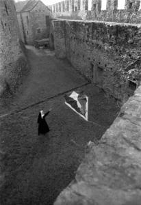 Ritratto femminile - giovane - modella travestita da suora gioca con un aquilone nel cortile di un castello. Lucy