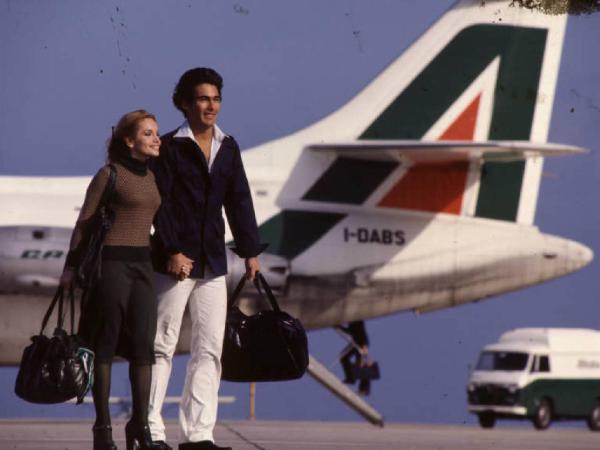 Alitalia. Coppia di modelli con aereo sullo sfondo