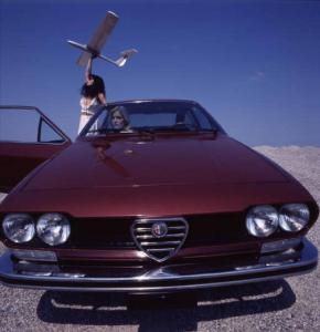 Campagna pubblicitaria Alfa GT coupé - fotomodella posa di fronte al veicolo con un modellino di aereoplano in mano - esterno
