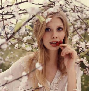 Campagna pubblicitaria Mon Chéri. Alberi di ciliegio in fiore - giovane donna assaggia una ciliegia