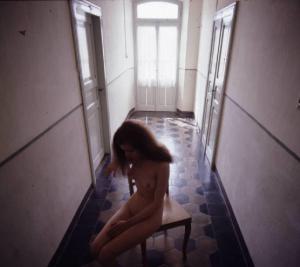 Ritratto femminile - modella nuda seduta in un corridoio