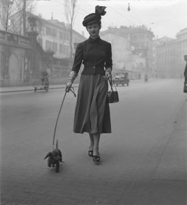 Italia Dopoguerra. Milano - Strada - Case - Ritratto femminile: modella con cane - Automobile