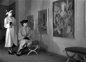 Italia Dopoguerra. Milano - Galleria Cardazzo, interno - Ritratto femminile: due modelle in posa - Quadri ai muri