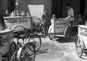 Italia Dopoguerra. Milano - Carretti con bicicletta di venditori ambulati di gelato - Gelataio e due bambini