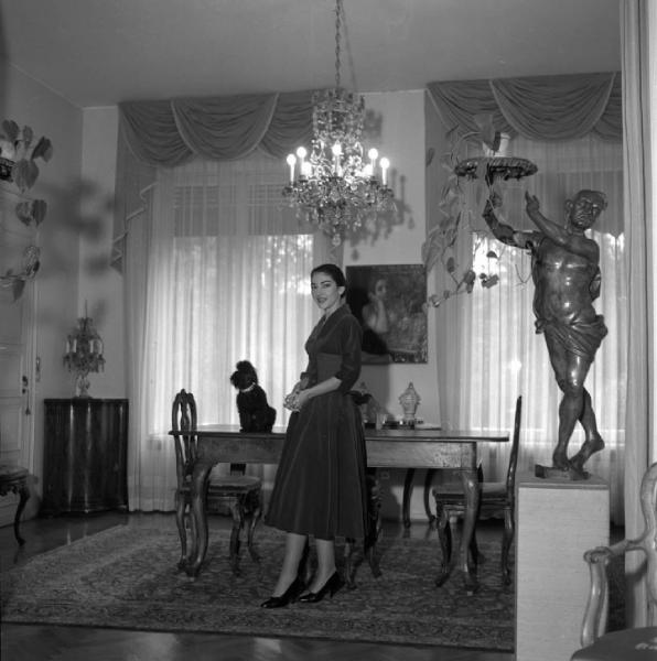 Milano - Abitazione di Maria Callas: interno - Sala da pranzo - Ritratto femminile a figura intera: Maria Callas (cantante lirica) - Cane barboncino sul tavolo