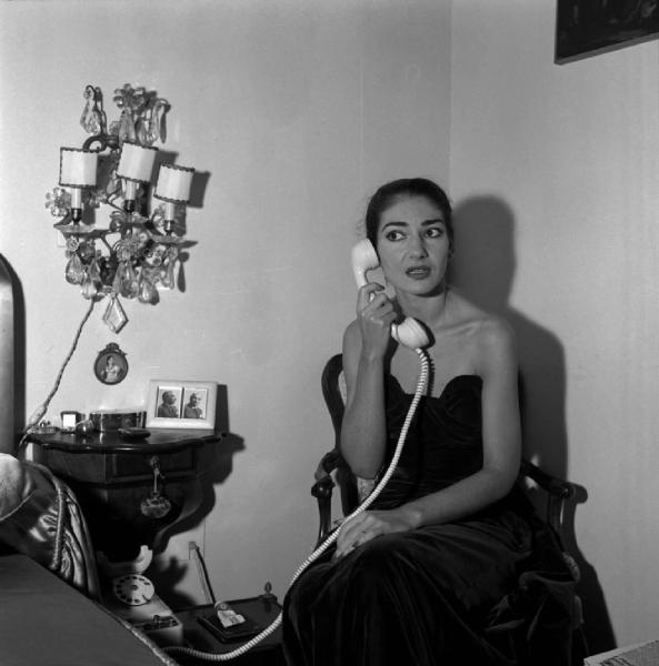 Milano - Abitazione di Maria Callas: interno - Camera da letto - Ritratto femminile: Maria Callas (cantante lirica) al telefono - Comodino con fotografie del marito Giovanni Battista Meneghini