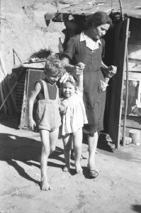 Italia Dopoguerra: Valmontone bombardata. Valmontone - Ritratto di gruppo: donna con bambini sulla soglia di una baracca
