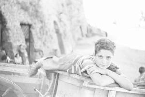 Italia Dopoguerra: Valmontone bombardata. Valmontone - Strada - Ritratto maschile: bambino disteso su carro di legno