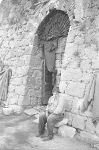 Italia Dopoguerra: Valmontone bombardata. Valmontone - Strada - Ritratto maschile: anziano seduto su una pietra - Mura in pietra - Porta