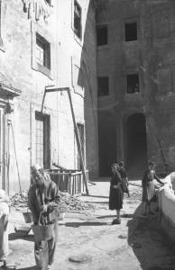 Italia Dopoguerra: Valmontone bombardata. Valmontone - Strada - Macerie - Ritratto di gruppo: operai al lavoro e donne