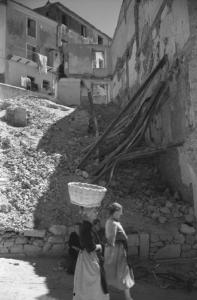 Italia Dopoguerra: Valmontone bombardata. Valmontone - Strada - Edifici bombardati - Macerie - Ritratto femminile di gruppo: donne con cesta sulla testa