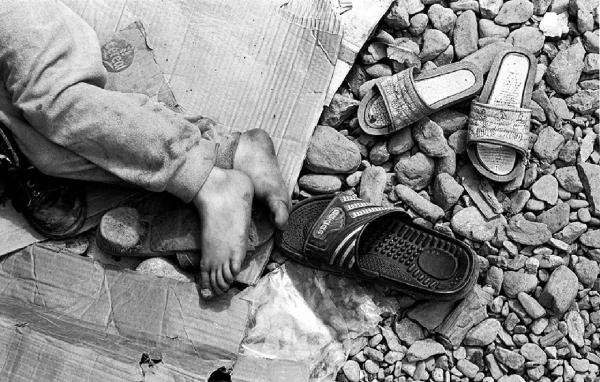 Balcani. Guerra dei Balcani - Albania - Profughi kosovari - Piedi di bambino sdraiato a terra - Ciabatte