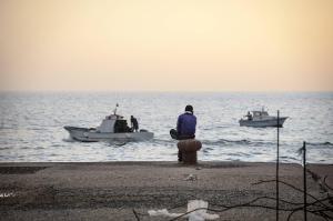 Migranti_Lampedusa. Lampedusa - Giornate dopo il naufragio del 3 ottobre 2013 - Mare - Banchina - Ragazzo seduto di spalle - Barche