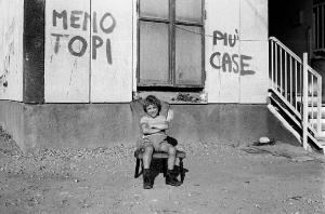 Altrove (1967-1980). Torino, periferia - Lotta per la casa - Scritta sul muro "meno topi più case" - Ritratto infantile: bambino seduto su poltrona in esterno