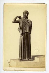 Figura femminile che si allaccia la veste sulla spalla destra - Dea - Scultura in bronzo