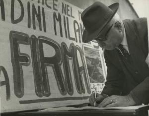 Milano - Raccolta di firme per la pace nel mondo - Ritratto maschile - Uomo con cappello firma la petizione - Striscione