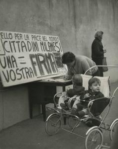 Milano - Raccolta di firme per la pace nel mondo - Una donna firma la petizione - Bambini su passeggino - Striscione