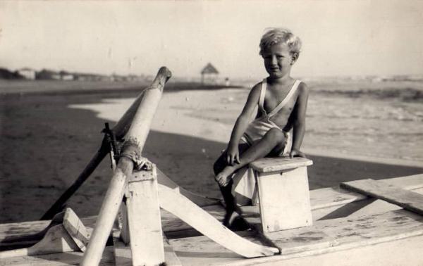 Ritratto infantile - Guido Stucchi bambino seduto su una barca in riva al mare