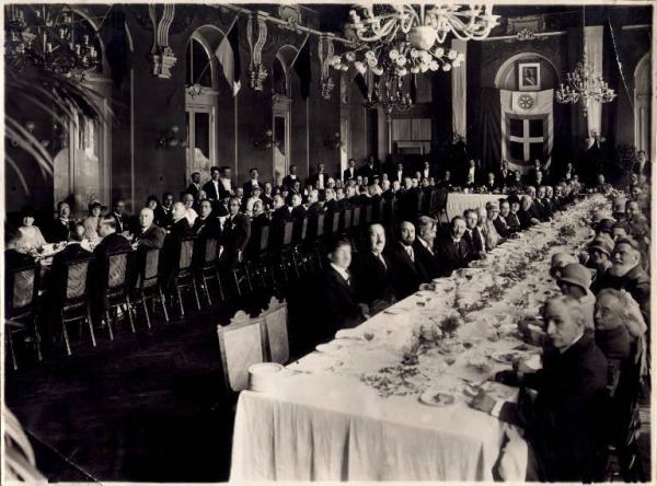 Ritratto di gruppo maschile e femminile - seduti attorno a un tavolo - durante una cena (?)