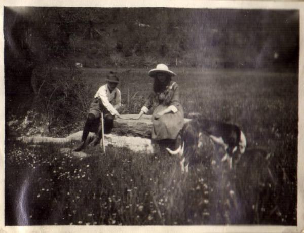 Ritratto di coppia - ragazzo e ragazza seduti in un campo con un levriero