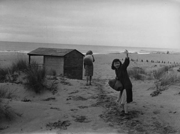 Scena del film "Senza pietà" - Regia Alberto Lattuada - 1948 - Le attrici Giulietta Masina e Carla Del Poggio con un sacco sulla spiaggia