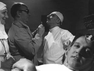 Set del film "Oh! Serafina" - Regia Alberto Lattuada - 1976 - Il regista Alberto Lattuda vestito da infermiere, due attori non identificati e l'attore Renato Pozzetto in primo piano