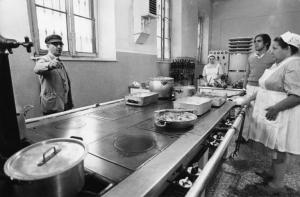 Set del film "Bianco, rosso e..." - Regia Alberto Lattuada - 1972 - Il regista Alberto Lattuada sul set con l'attore Adriano Celentano in cucina con due attrici non identificate